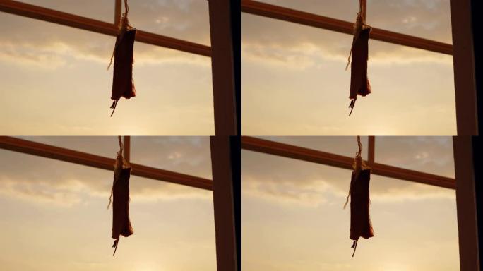 绳子上的老式音符挂在窗户上，在背景中，海洋或海洋上有美丽的日落，阳光照进相机。纸条挂在门口。