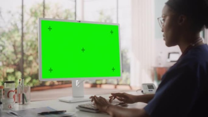 多民族保健护士使用带有绿屏模拟显示的台式计算机进行日常医院操作。黑人诊所专业人员使用PC进行在线医疗