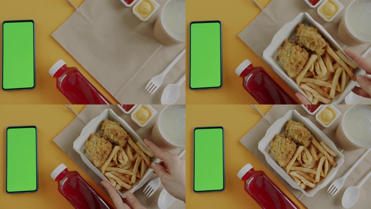 黄色背景上热即食手和绿屏智能手机的特写