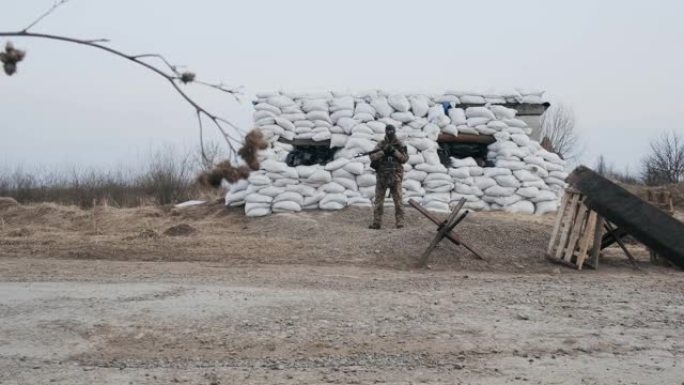 身穿军装、手持武器的士兵站在由沙袋和反坦克刺猬屏障制成的路障旁。路障上有军人。