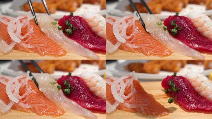 用筷子吃新鲜生鱼片。鲑鱼、大比目鱼、红蛤蜊和对虾。特写