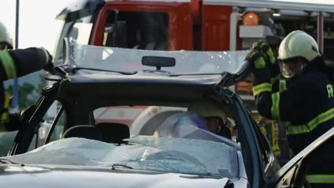两名消防员抬起他们穿过的车顶，帮助一名受伤的男子