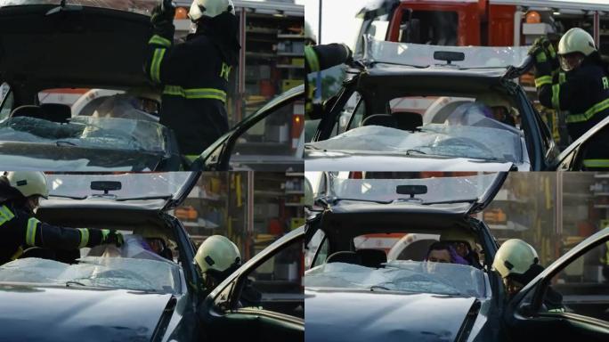 两名消防员抬起他们穿过的车顶，帮助一名受伤的男子