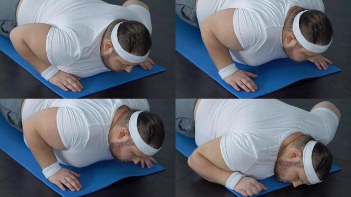 胖子摔倒在瑜伽垫上试图做木板运动，缺乏能量
