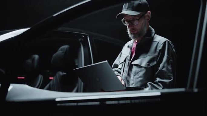 经销商汽车机械师的肖像分析了现代电动汽车的诊断结果。在笔记本电脑上工作的软件开发人员，研究现代可持续