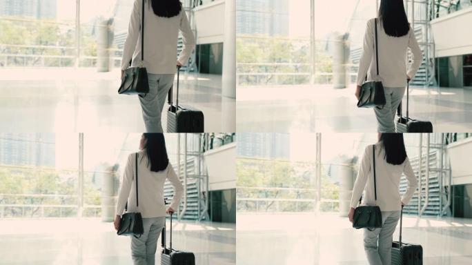 旅行保险带旅行，商务妇女在机场带着手提箱散步，商务旅行。背光色调。