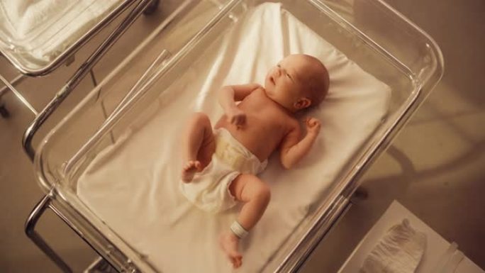 精力充沛的高加索新生儿躺在托儿所的病床上。顽皮健康的小宝宝。医疗保健、生育和生育概念。暖色等级和高角
