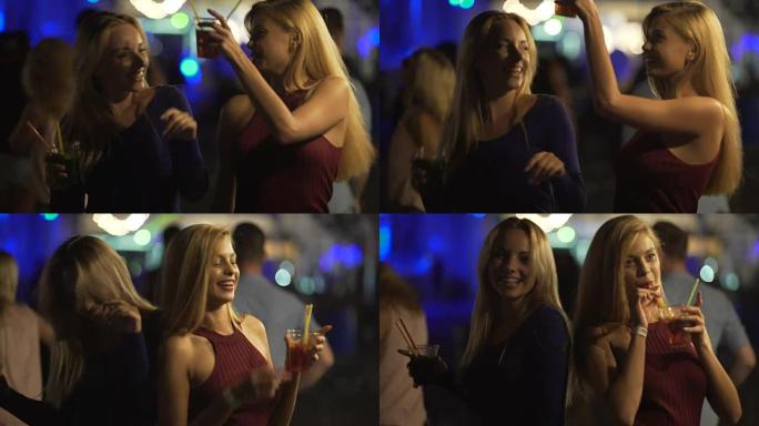 快乐的女性朋友在舞池里享受派对，叮当叮当的鸡尾酒杯