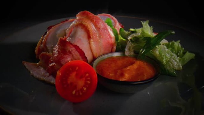 将热而油腻的火腿切片放在带有萨拉特，番茄和酱汁碗的盘子上