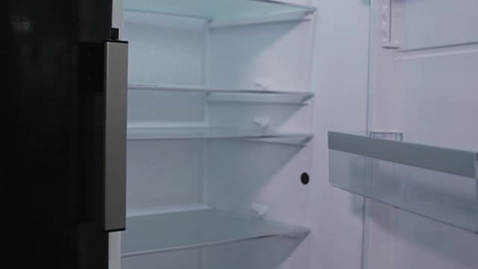 女性展示空空的冰箱货架，表示失望，危机