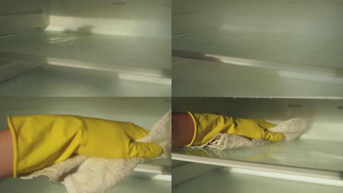 特写镜头，面目全非的男性戴着黄色手套用蒸汽清洁器清洁空冰箱，用布做家务洗架子。