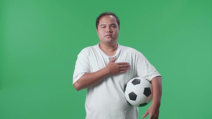 亚洲男子在绿屏背景上欢呼足球时唱着国歌