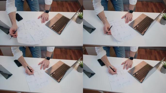顶视图。手握着大型纸张格式方案上的钢笔绘图线，在工程领域的桌子上工作，集中精力并绘制蓝图。