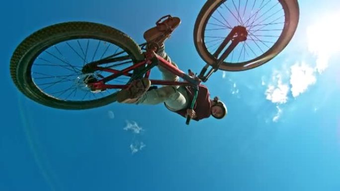 SLO MO DJ骑自行车的人在阳光下旋转