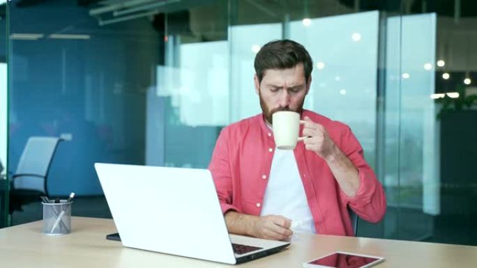 生病不健康的商人自由职业者喝杯热饮料时，在电脑上工作时会打喷嚏流鼻涕