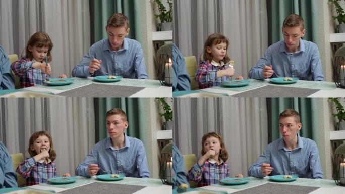 一个哥哥和姐姐坐在家里的桌子旁吃饺子