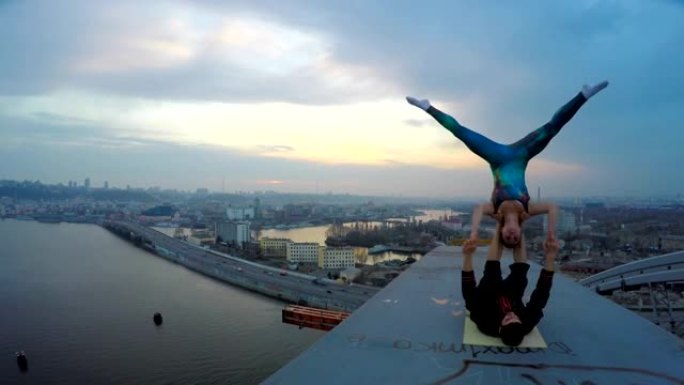 勇女人和男人在桥顶做极端特技，美妙的城市景观