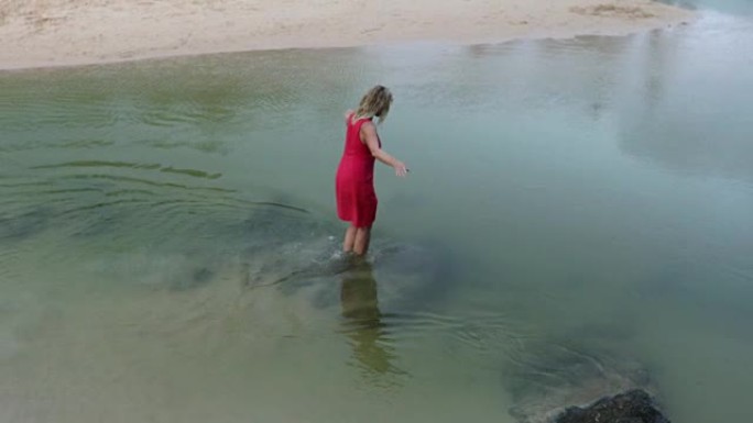 女人涉水进入清澈的溪流，抚摸水面