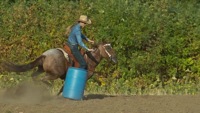 骑着马的女人以超慢动作绕过桶