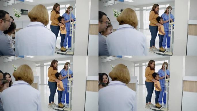 护士带孩子在医院里称体重并测量他的身高。