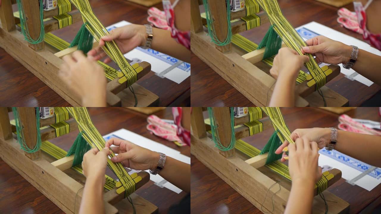 用于分离纱线的手指，以使绿色纱线的织布机在编织过程中穿过，以创建传统的亚洲图案，并在肩膀上近距离拍摄