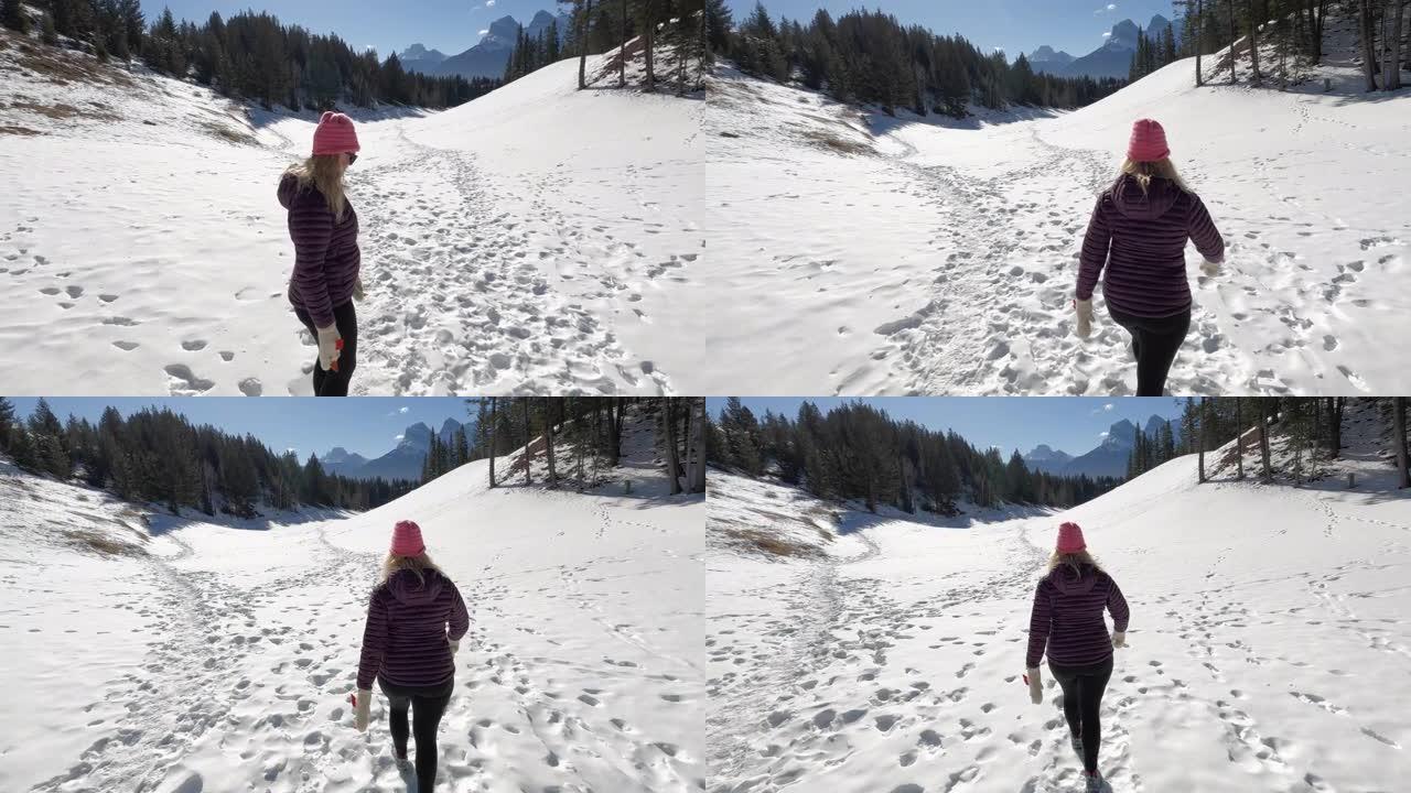 成熟的女人在高山环境中沿着雪道行走