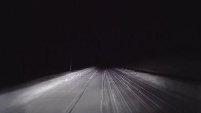 晚上在森林的雪路上开车。