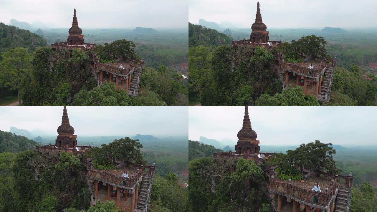 站在泰国丛林山上的佛教寺庙中的女人的鸟瞰图