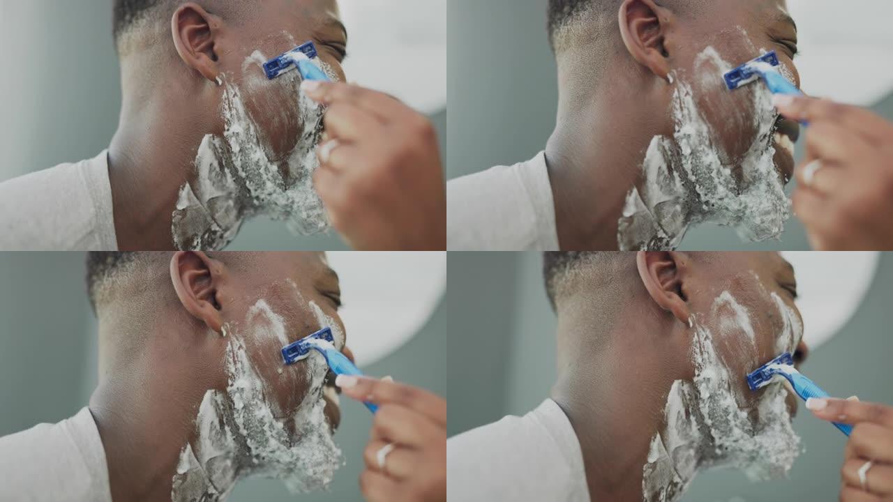 黑人，手和帮助在家里的浴室用剃刀刀片做剃须膏，美容或卫生。非裔美国男性面部和女性的手协助面部剃须，治
