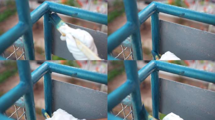 工人使用柔软的画笔为阳台铁框涂漆蓝色，修理工用现代高效化学溶液重建旧金属表面，用风化腐蚀更新钢表面