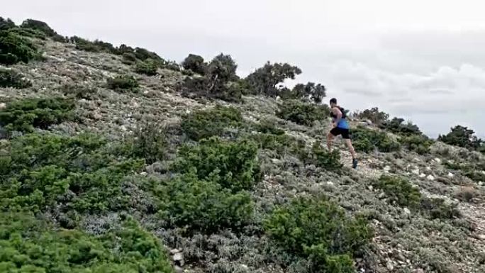 空中男性跑步者在岩石小径上跑上一座山