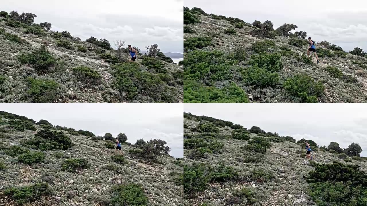 空中男性跑步者在岩石小径上跑上一座山