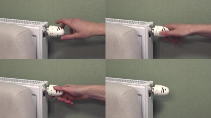用手关闭家用散热器旋钮阀门的热量。加热器功耗降低、节约理念