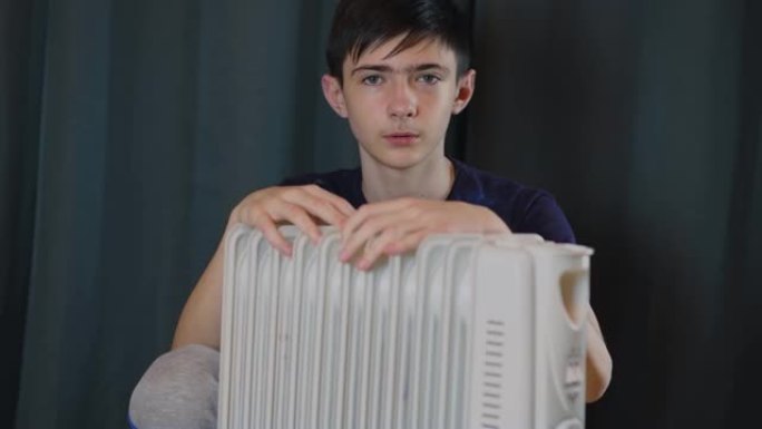 放松自信的男孩坐在电加热散热器和温暖的手附近