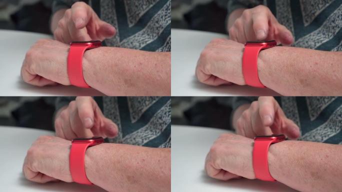 老年女性手腕特写上的红色时尚智能手表。成年女性在可穿戴小工具的屏幕上打字和触摸手指。