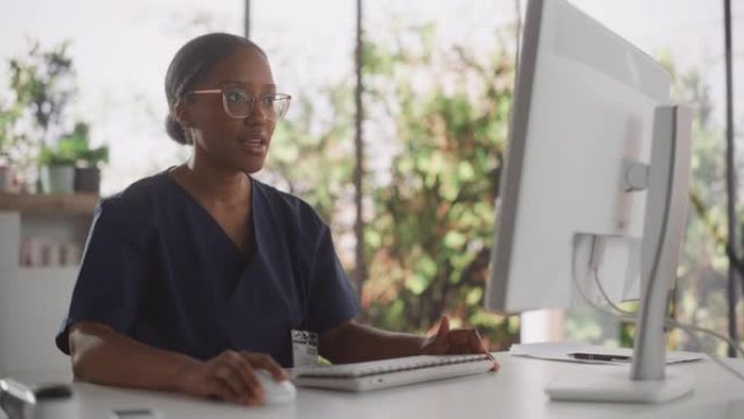 非洲保健护士使用台式计算机进行日常医院运营。美丽的年轻诊所专业人员使用PC在公共卫生保健机构的现代办