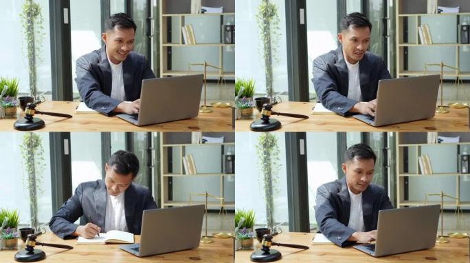 亚裔男子律师肖像在使用计算机和笔记本上班前为客户研究案件