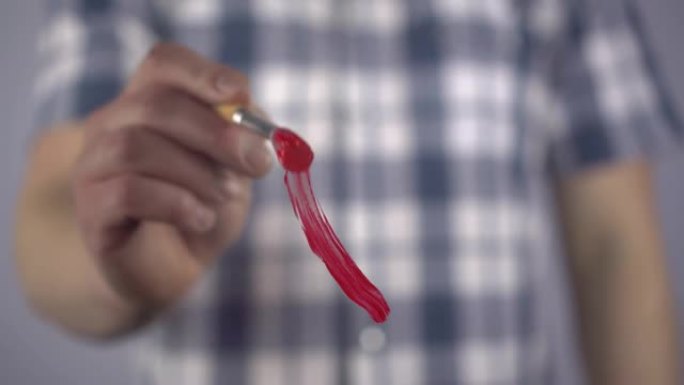 一个年轻人用刷子将艾滋病毒的象征画成红色。一名男子在玻璃上画了一个红丝带环，以支持癌症患者。特写。4