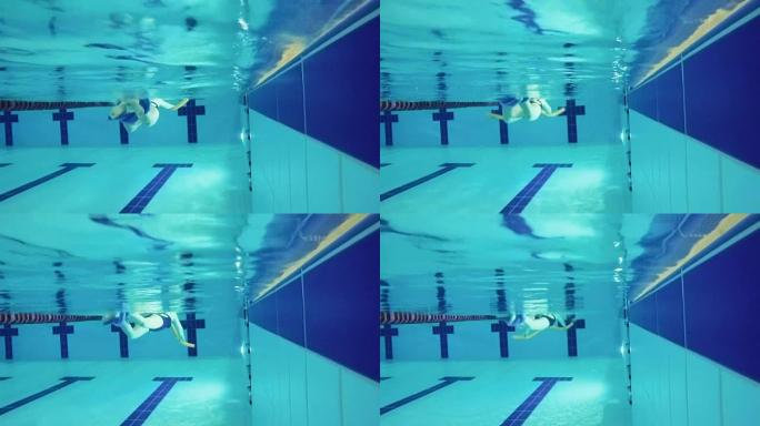 高级女子在游泳池用特殊设备游泳-水下