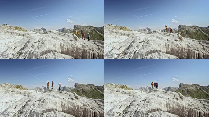 晴天，三名登山者在高山的岩石地形上行走