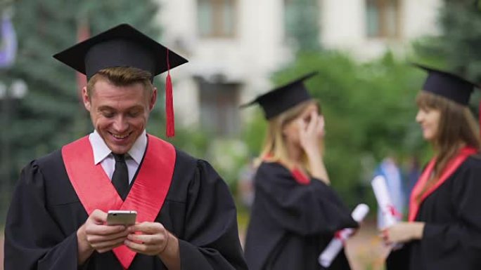 学院附近的智能手机上的毕业生浏览，背景上的朋友聊天