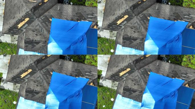飓风伊恩房屋屋顶上覆盖着蓝色防护篷布的受损鸟瞰图，以防雨水泄漏，直到更换沥青瓦为止