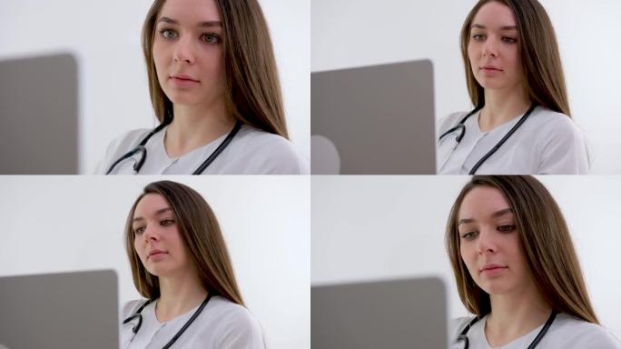 女医疗助理穿着白大褂，耳机视频在笔记本电脑上给远方病人打电话。医生使用虚拟聊天计算机应用程序与客户交