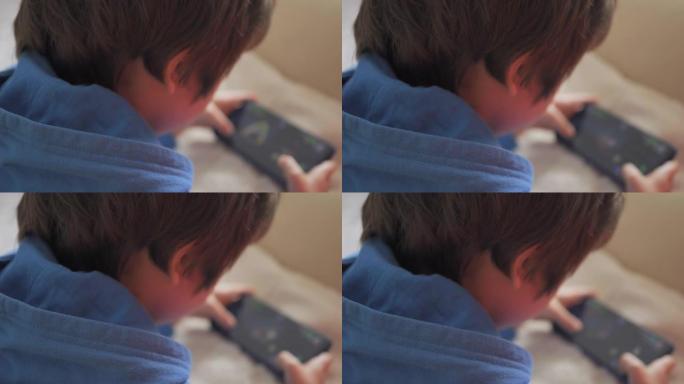 孩子躺在沙发上在家打电话玩游戏。男孩在手机上玩电子游戏。学龄前儿童在沙发上玩电子游戏智能手机。孩子使