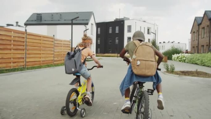 两个不同的孩子骑着自行车在住宅区周围骑行