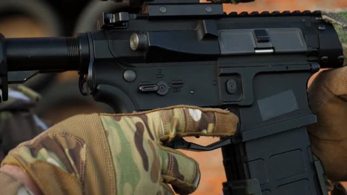 一名军人将手指扣在自动步枪的扳机上。