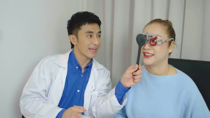 年轻的亚洲男子眼科医生在眼科诊所做眼科测试高级女性，拿着封堵器看图表，视力矫正，光学诊所，健康概念。