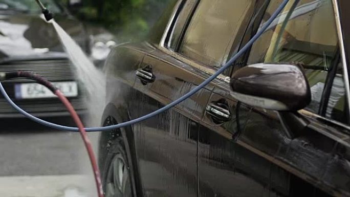 工人清洁汽车，在车辆上喷水，成功的洗车业务