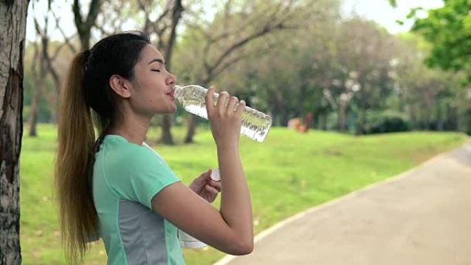 女人在公园里喝凉水，女人在跑步腰带上听音乐。