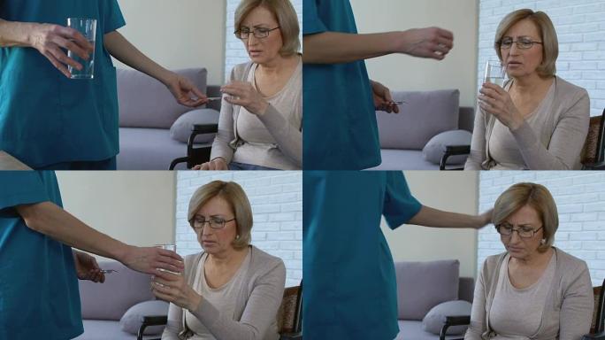 女护士给坐在轮椅上的不舒服的女人吃药，支持老太太